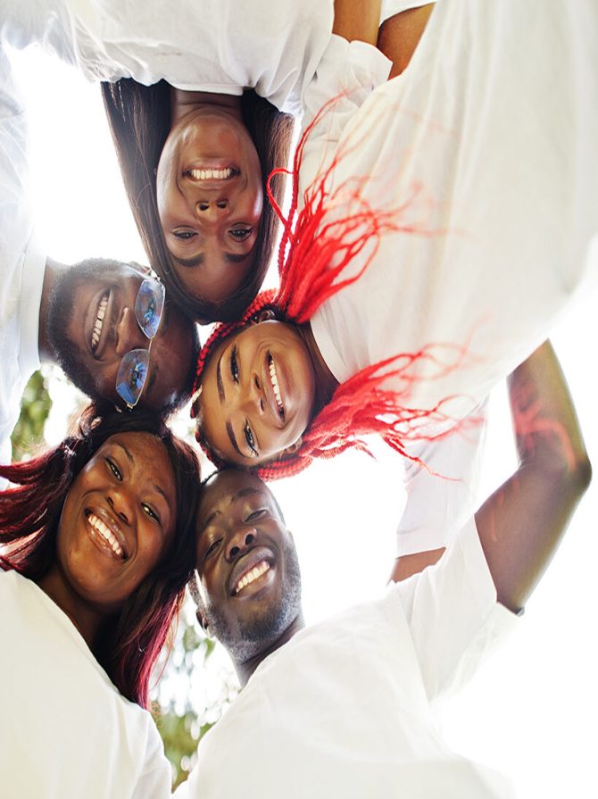 Group of happy african volunteers hugs in park. Africa volunteering, charity, people and ecology concept. Look from down.