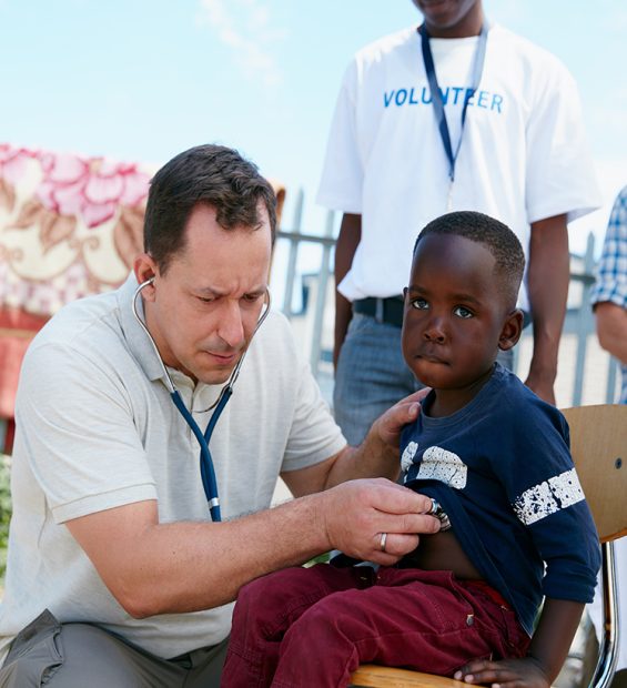 Shot of a volunteer doctor examining a young patient with a stethoscope at a charity event.